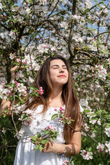 Young caucasian woman enjoying the flowering of an apple trees