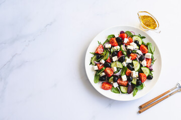 Greek salad of fresh cucumber, tomato, red onion, feta cheese and olives with olive oil. Healthy food, top view