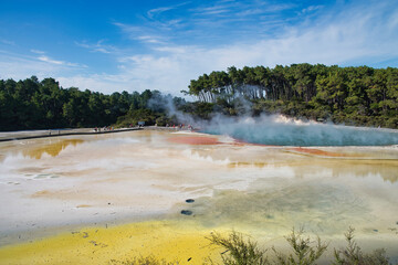 Tourists standing in the middle of a natural wonder of a hot vulcanic lake in Rotoroa creating colorful, orange and yellow, sulphur covered areas. New Zealand, North Island