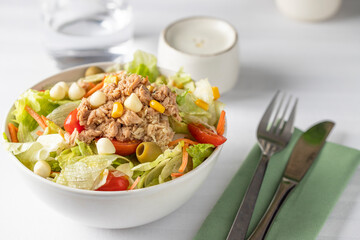 Close up of tuna salad bowl with different lettuce and vegetables on the restaurant table - obrazy, fototapety, plakaty