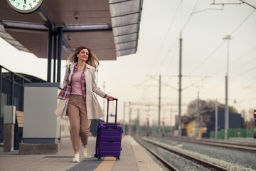 Front view of a woman with suitcase running to catch the train before it leaves the station without her.