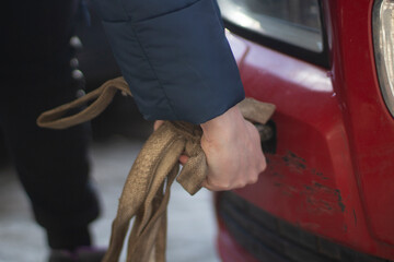 Cable for car. Guy hooks car for towing. Hand holds carabiner for screwing into bumper of car.
