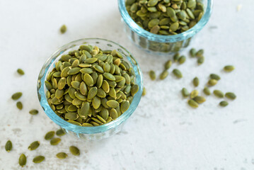 pumpkin seeds in glass bowl on white marble table background.