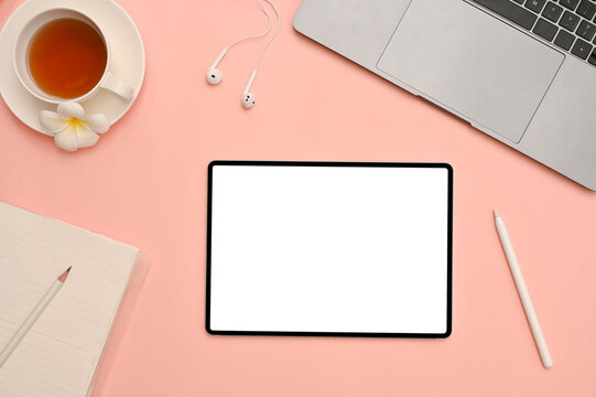 Lovely feminine workspace office desk top view with tablet mockup on pink background.