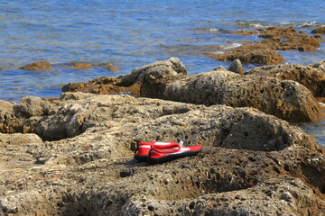 Red water shoes on a shore.