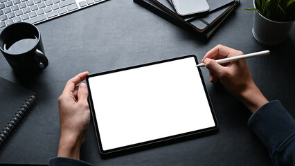 A man using stylus pen and working on digital tablet at his workspace.