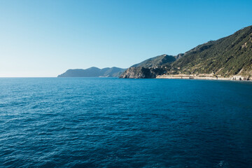 Fototapeta premium Beautiful seascape with blue sky, smooth water surface and rocky cliffs in Liguria coastal area. Popular italian travel destination.