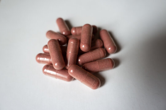 Fistful of pink capsules of PQQ dietary supplement
