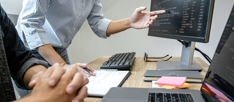 Two professional programmer cooperating and working on web site project in a software developing on desktop computer at company, codes and typing data code, Programming with HTML, PHP and javascript