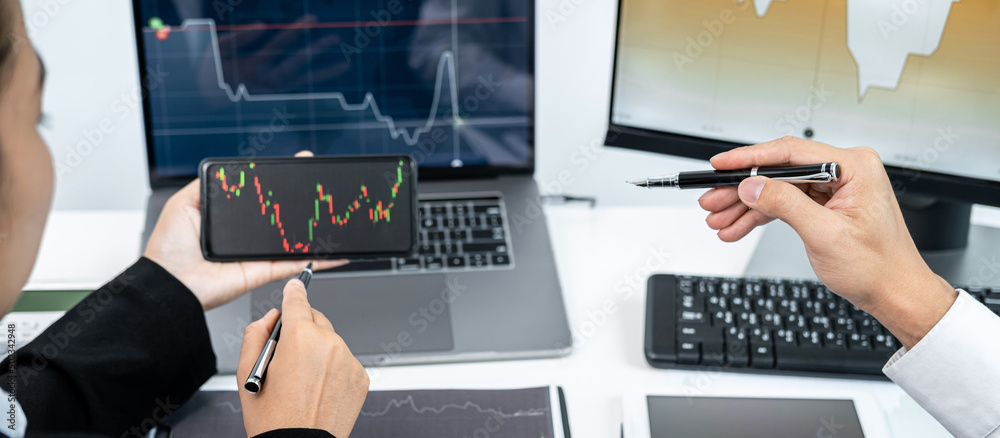 Poster Two business colleagues pointing stock data chart on smartphone to checking data stock market and discussion