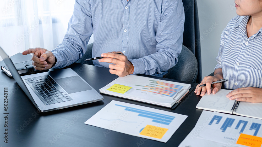 Aufkleber two business colleagues pointing business data on laptop and taking notes information on notebook wh