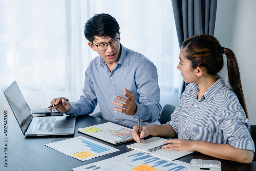 Poster two business colleagues pointing business data on laptop and taking notes information on notebook wh