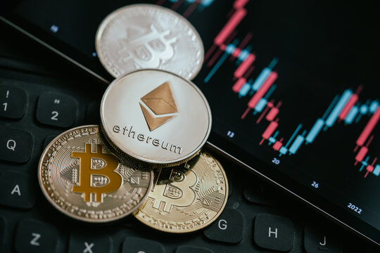 Gold Bitcoin and Ethereum cryptocurrency coins with candle stick graph chart, laptop keyboard, and digital background,  in Bucharest, Romania, on April 3, 2022.