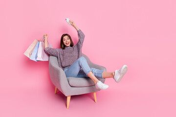 Portrait of attractive cheerful girl using device holding bags order deliver having fun isolated...