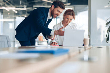 Smiling office worker shows creative project mature female businesswoman on laptop. Business concept