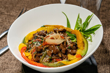 Meat salad with vegetables, asparagus and fresh herbs in a white plate. Close-up