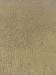 Glistening rippled shallow water on white sand beach. Natural background