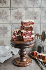 Chocolate brownie with cherries and cheese layer. Many pieces of chocolate dessert with berries on a wooden board	