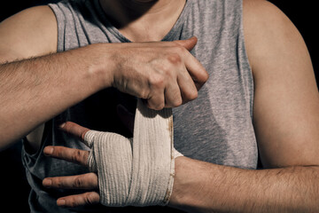 Fototapeta na wymiar A fighter bandages his hands before a fight. Boxer getting ready for sparring. Protection of hands from fracture.