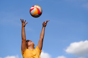 The girl plays volleyball. The child catches the ball with his hands. outdoor play.