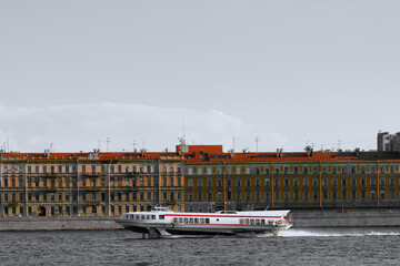 Naklejka premium The ship is sailing on the river. A pleasure boat with tourists travels through the canals of a European city. Water tourism.