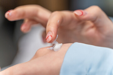 girl smears cream on her hand in blue pajamas