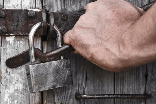 A man breaks the lock on an old door. House burglary.