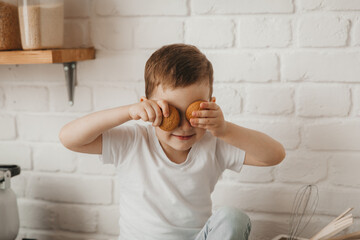 cute little boy sitting on the counter in a stylish kitchen with his bare feet dangling