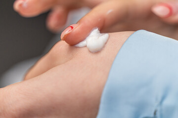 girl smears cream on her hand in blue pajamas