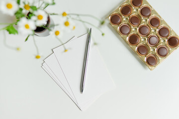 Light colorful holiday banner. Flowers on a marble background with a card and a pen. Mother's day, birthday, celebration concept, congratulations. Copy space, top view, greeting card banner.