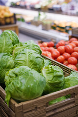 Fresh spring cabbage and tomatoes on counter, vegetable department in grocery store, supermarket. healthy food, green vegetables