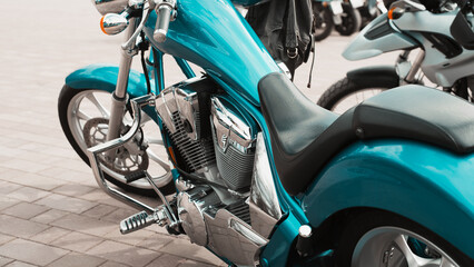 Fototapeta na wymiar Cyan chrome stylish bike parked outdoors. Close-up of custom motorcycle with shiny details