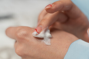 girl smears cream on her hand in blue pajamas