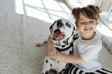 Child with a dog. A happy girl lies on a carpet with a Dalmatian dog. High quality photo