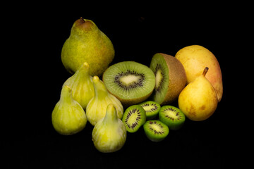Fototapeta na wymiar Kiwi fruit and yellow kiwifruit, juicy figs, pears and avocado, on black background