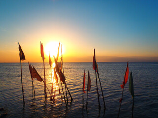 Flags in the sea at the Temple by The Sea in Trinidad Island with a sunset on background.