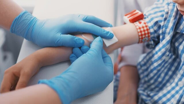 doctor or nurse takes blood from a vein in a child of a boy. Blood chemistry