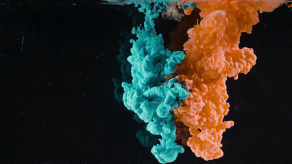 Splash of colored ink in water on black background. Action. Two colors are mixed in water on isolated background. Close-up of colored ink beautifully submerged in water in slowmo