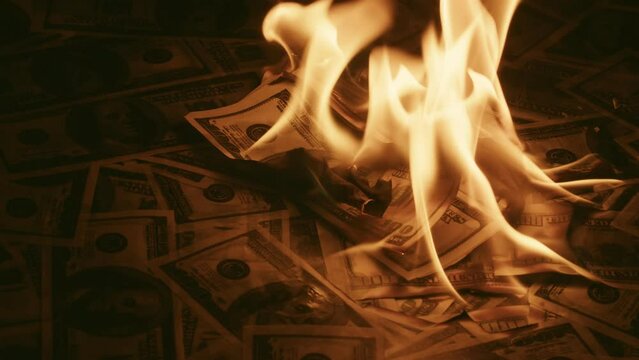 Lot of money burns quickly, closeup. Dollar is burning with bright flame. Concept of ruin and crisis