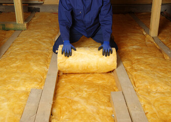Man installing thermal insulation layer under the roof