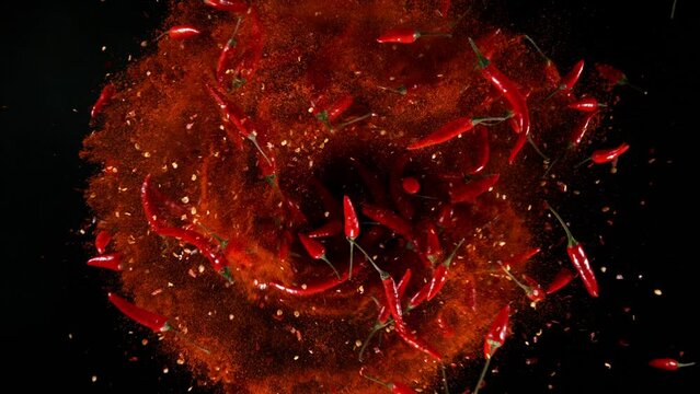 Super slow motion of rotating chilli peppers isolated on black. Overhead view, filmed on high speed cinema camera, 1000 fps. Ultimate perspective and concept of flying food.
