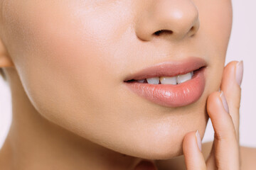 Pure beauty. Cropped photo of young blonde woman touching her soft and fresh skin while standing against grey background. Skin care