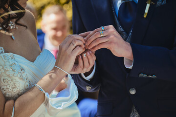 Fototapeta premium Close up of the hands of a bride and groom giving each other wedding rings