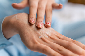 girl smears cream on her hand in blue pajamas