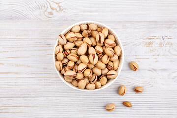 A bowl of pistachios on a wooden table. Top view. Close-up. 