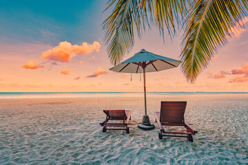 Beautiful tropical sunset scenery, two sun beds, loungers, umbrella palm leaves. Sand, sea view horizon, colorful sunrise sky. Tranquil dusk beach resort. Romantic beach, island paradise landscape
