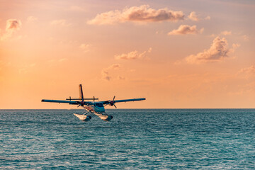 Naklejka na ściany i meble Exotic scene with seaplane on Maldives sea landing. Seaplane landing on sunset sea. Vacation or holiday in Maldives concept background. Air transportation, Landing seaplane on the dawn seashore