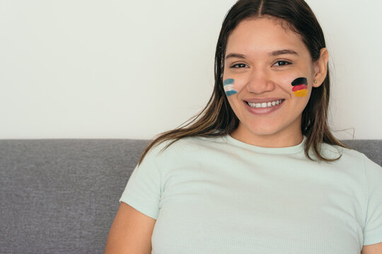 Soccer Fan Cheering At The Game With Colored Paint On Her Face.