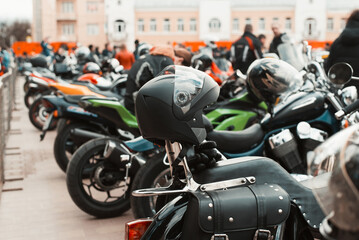 Obraz na płótnie Canvas Side view of group of parked racing bikes outdoors, opening of moto season. Selective focus on motorcycle helmet, close-up