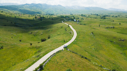 Aerial footage a car driving over Beautiful green mountain road in Pisce, Montenegro